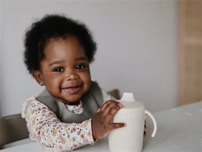 Mushie tudekop i blush med låg og håndtag- barn holder hvid kop