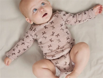 Baby iført Name It uld body i shadow gray med sløjfeprint