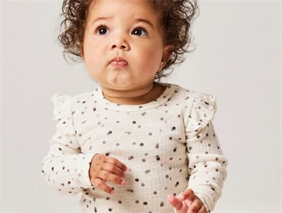 Baby klædt i Name It ribbody i råhvid nuance med flæser ved skuldrene
