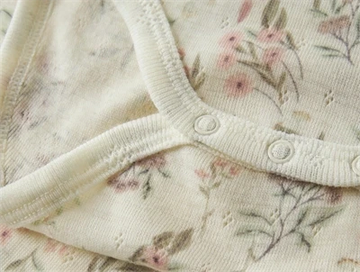 Name It råhvid bodystocking i merinould til baby med blomster