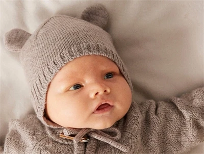Baby klædt i Name It merinould hue i beige nuance med bamseører