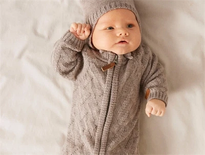 Baby klædt i Name It strikdragt i gråbrun nuance med kabelstrik