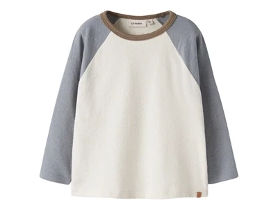 Lil' Atelier bluse i råhvid nuance med blå raglanærmer set forfra