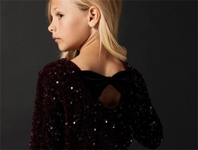 Pige iført Name It burgundy pailletkjole med sort sløjfe