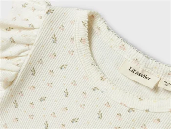 Nærbillede af ribstruktur og blomsterprint på Lil\' Atelier t-shirt i coconut milk
