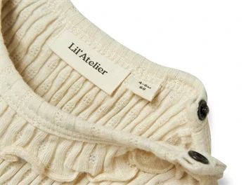 detaljebillede af trykknapper og struktur på lil\' atelier body i råhvid