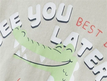 nærbillede af alligatorprint og tekst på beige Name It t-shirt