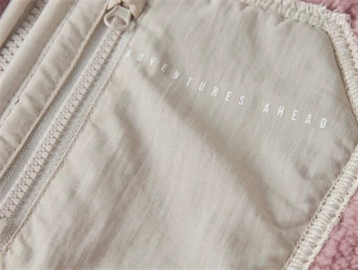 Detalje af brystlomme med tekst Adventures Ahead på Name It teddy jakke