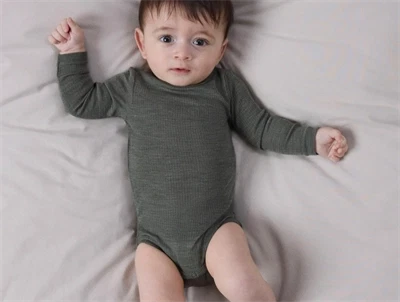 Baby klædt i Name It body i mulled basil i merinould