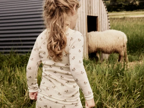 Pige klædt i Lil\' Atelier merinould bluse i råhvid nuance med blomsterprint