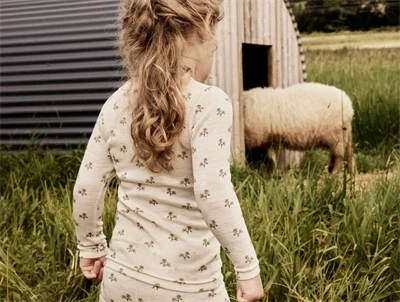 Pige klædt i Lil' Atelier merinould bluse i råhvid nuance med blomsterprint