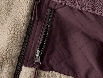 Detalje af lynlåslomme på Name It Kids teddy jakke i råhvid og lilla nuance