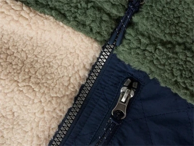 Detalje af lynlåslomme på Name It Kids teddy jakke i råhvid og grøn nuance