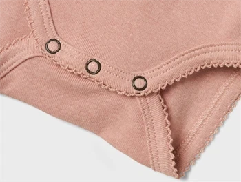 Nærbillede af trykknapper og kantdetalje på Lil\' Atelier body i misty rose
