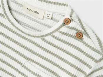 Nærbillede af knaplukning og stribet struktur på Lil\' Atelier t-shirt
