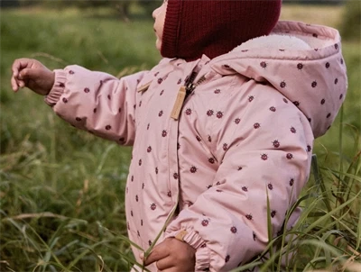 Baby i Lil\' Atelier flyverdragt rosa med mariehøneprint udendørs