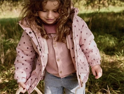 Barn iført Lil\' Atelier jakke rosa med mariehøneprint udendørs