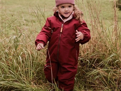 Lil' Atelier flyverdragt i rød red dahlia med fleecefor set på barn i natur