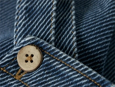 Detalje af knap og syninger på Lil\' Atelier denim overalls i blå