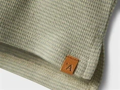 lil\' atelier top i støvet grøn med vævet mærke og struktur, tæt på søm