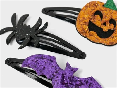 Nærbillede af Name It hårspænde med lilla flagermus, sort edderkop og orange græskar