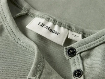 Nærbillede af hals og trykknapper på Lil\' Atelier body i seagrass