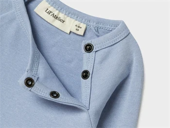 Nærbillede af hals og trykknapper på Lil\' Atelier body i zen blue