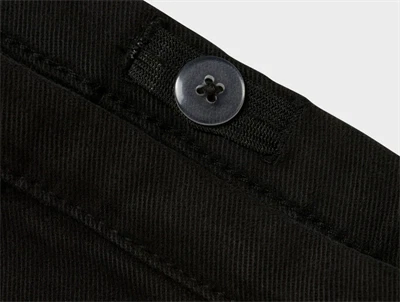 Detalje af knap og linning på Name It sort twillnederdel