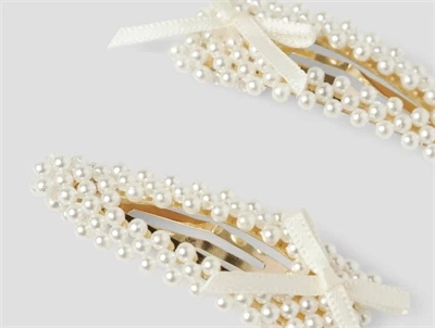 Detaljebillede af hårspænder i hvid fra Name It med perler og sløjfe