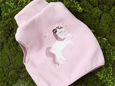 Name It teddyvest i rosa nuance på græs med enhjørning motiv på ryggen