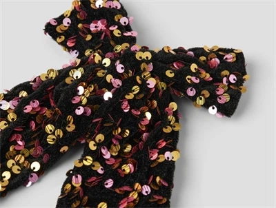 Detaljebillede af hårsløjfe fra Name It i sort med guld og pink pailletter