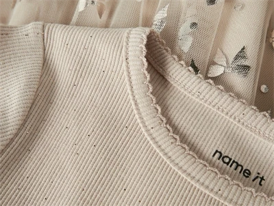 Detalje af ribstrikket overdel og tylskørt med sløjfer på cementfarvet kjole fra Name It