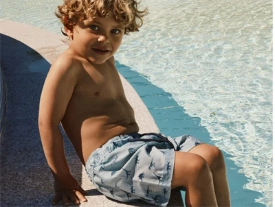 Dreng iklædt Name It badeshorts blå nuance med dinosaur print til børn