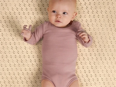 Barn iklædt Lil' Atelier body i rosa nuance med hulmønster