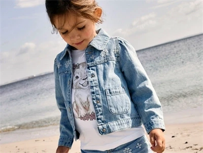 Pige iklædt Name It denimjakke i lys blå nuance med blomsterbroderi 