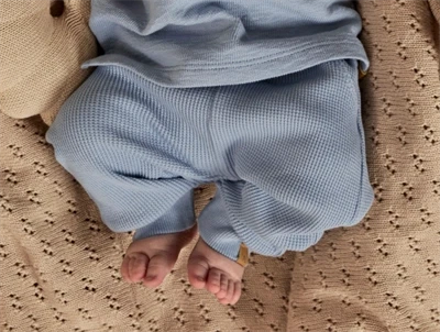 Baby iklædt Lil Atelier bukser i blå nuance med ribkanter og snøre