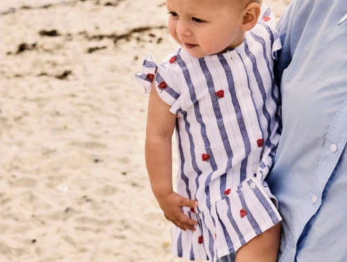 Lille pige iklædt Name It kjole i råhvid nuance med blå striber og jordbær