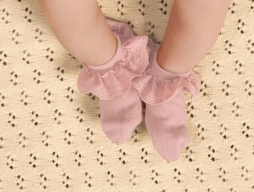 Baby iklædt Lil\' Atelier strømper i rosa nuance med flæsekant
