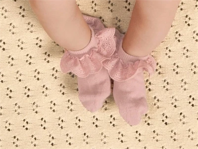 Baby iklædt Lil' Atelier strømper i rosa nuance med flæsekant