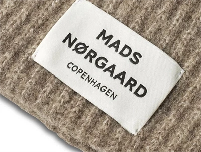 Logolabel på Anju hue i brun nuance fra Mads Nørgaard