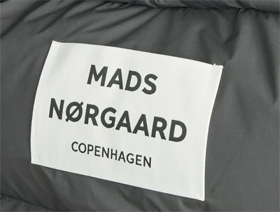 Nærbillede af Mads Nørgaard logo på mørkegrå puffetaske