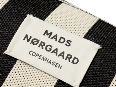 Nærbillede af logo på sort og hvid stribet tote bag fra Mads Nørgaard