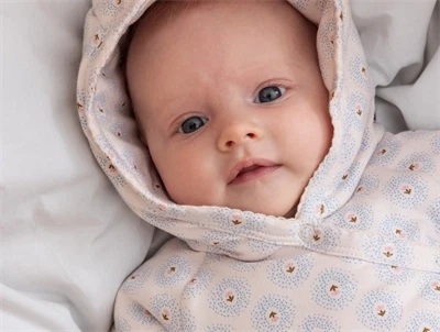 Baby med hætte iført MarMar køredragt i farven little tulip
