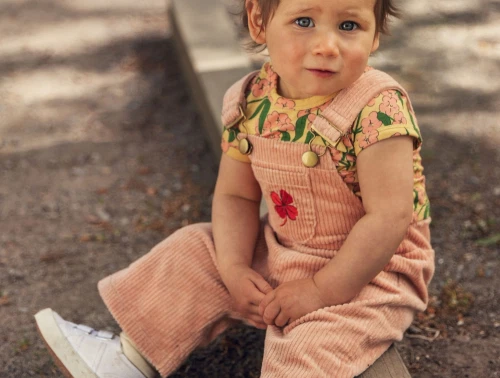 Barn iført peachfarvede fløjlsdungarees fra Mini Rodini med firkløverbroderi