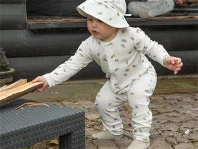 Barn iklædt Joha heldragt i råhvid nuance med krabbeprint i uld og silke