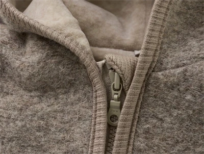 Huttelihut køredragt i camel melange med blød uld og hætte set tæt på lynlås