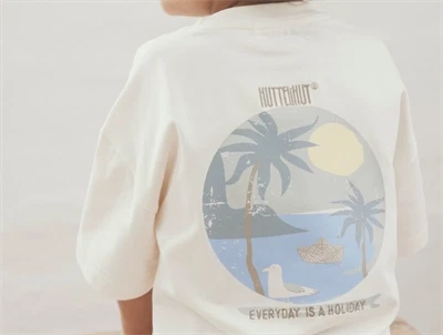 Dreng iklædt Huttelihut t-shirt i råhvid med brystlomme og print på ryggen