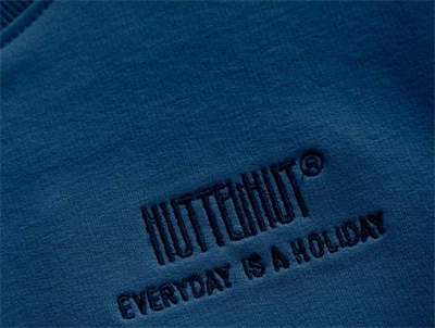 Detalje af blå Huttelihut sweatshirt med broderet logo foran