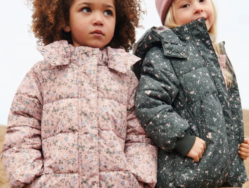 Wheat pufferfrakke i rose powder flowers bæres af barn med jakke i grøn print ved siden af