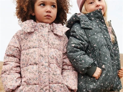 Wheat pufferfrakke i rose powder flowers bæres af barn med jakke i grøn print ved siden af